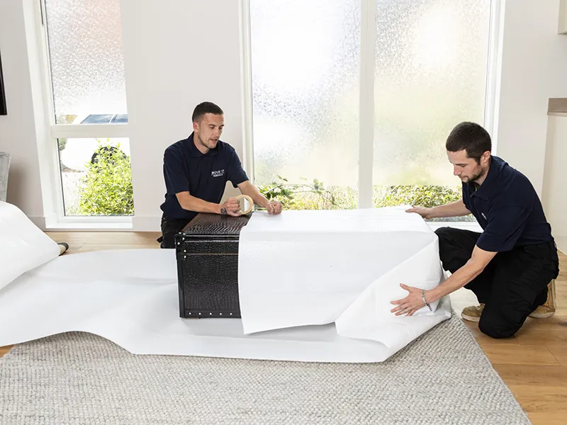 Move It Removals movers wrapping a chest in protective bubble wrap before shipping