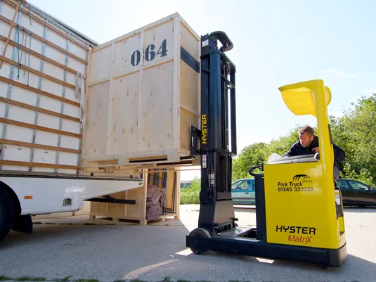 Forklift loading a wooden Move It Removals shipping crate onto a lorry in Essex
